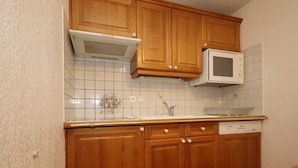 A kitchen with wooden cabinets, a microwave, and a tiled backsplash. - 2-room apartment, 5 pers., skiing, parking, pool (Les Houches)