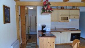 A compact kitchen with wooden cabinets, a built-in microwave, and a small island with a toaster.