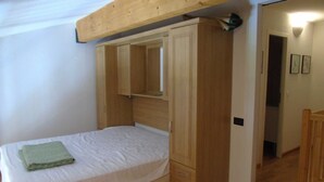 A bedroom with a bed, wooden wardrobe, and a mirror.