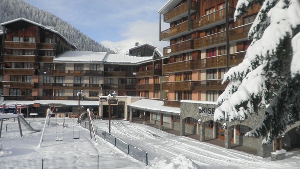 A multi-story hotel with balconies and a ski slope in the foreground.