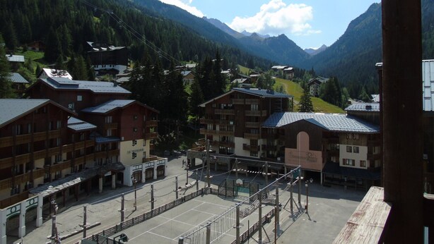 Un rifugio alpino con edifici in stile chalet, una seggiovia e una vista chiara sulle montagne circostanti.