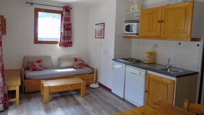Una cucina compatta con un tavolo di legno, un forno a microonde integrato e un piccolo frigorifero.