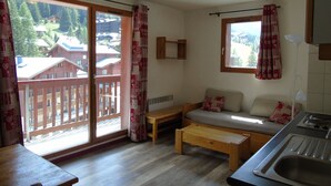 Una stanza accogliente con una panca in legno, un divano, un tavolino e vista su un pontile in legno e edifici esterni.