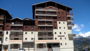 Un hotel a più piani con balconi, facciata in pietra e parcheggio.