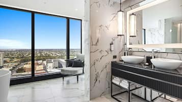 A modern bathroom with a large window, marble walls, and a dual sink vanity.