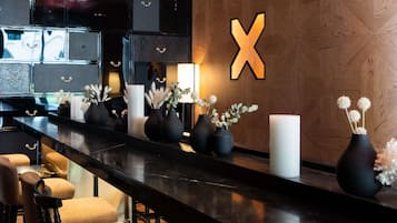 A bar area with a long counter, black bar stools, and vases with flowers.