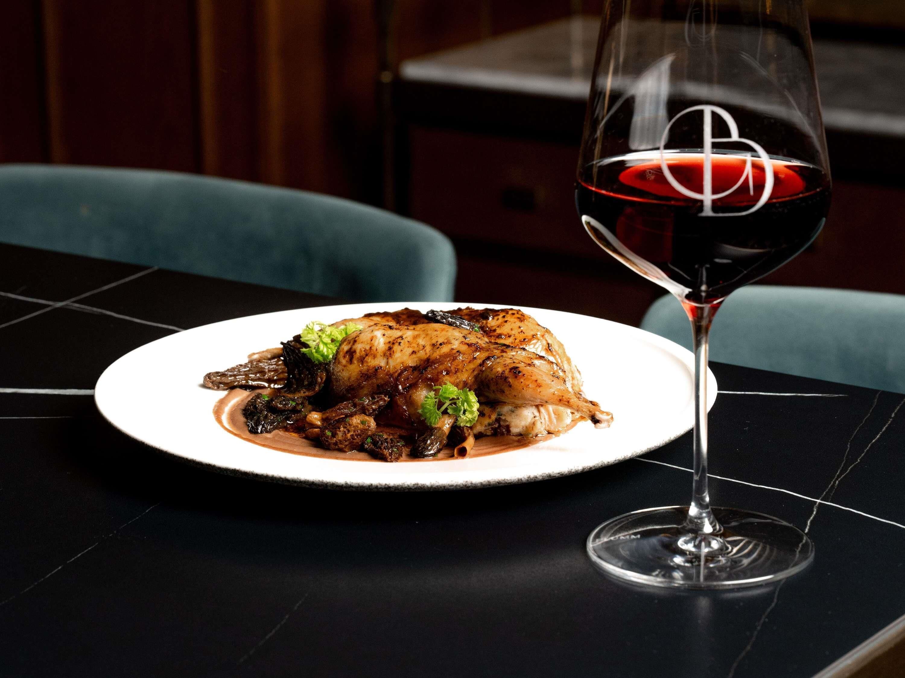 A plate of food and a wine glass on a table.