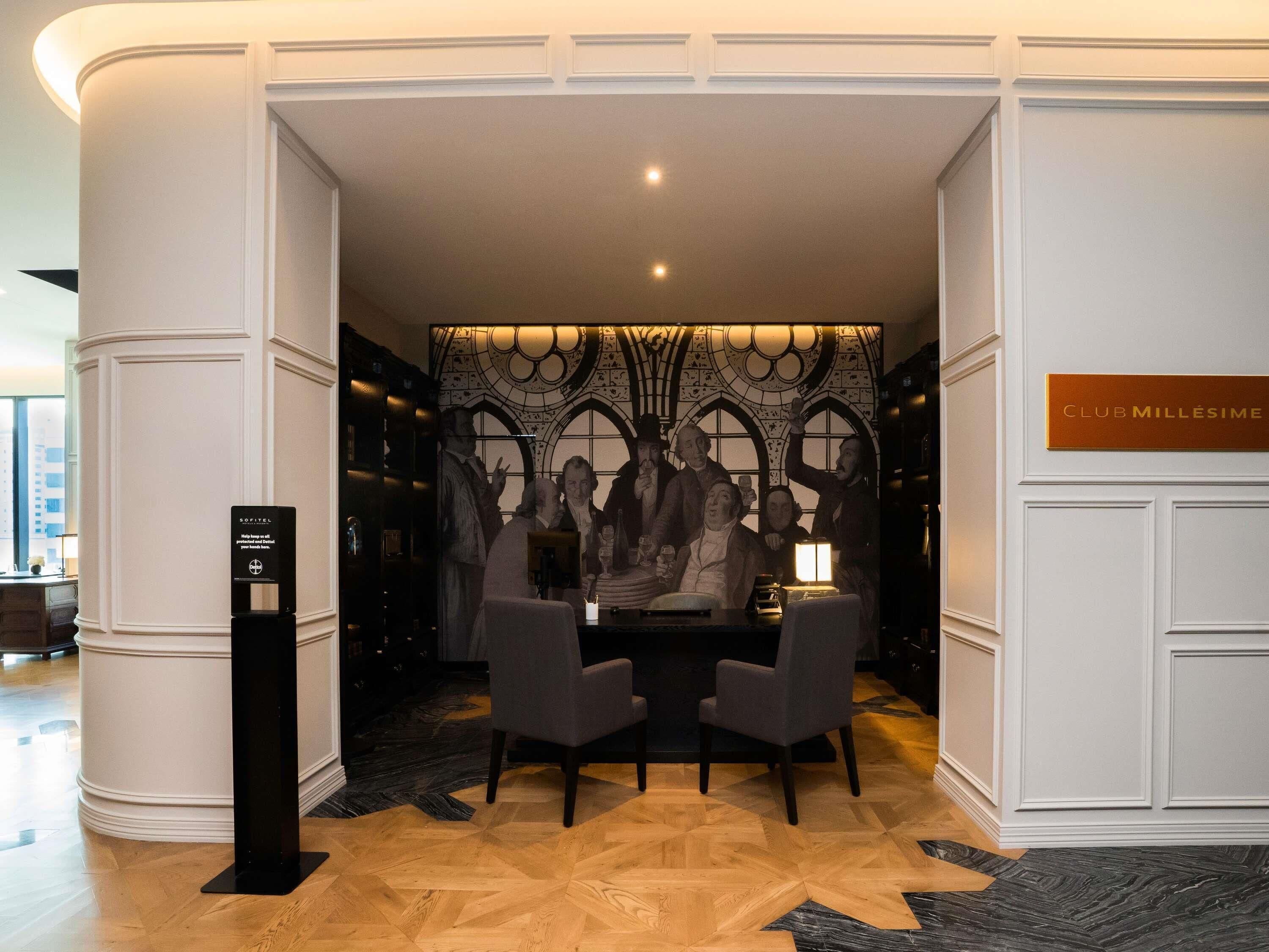Un hall con una mesa y sillas, una pared decorativa y un cartel que dice 'CLUB MILLÉSIME'.