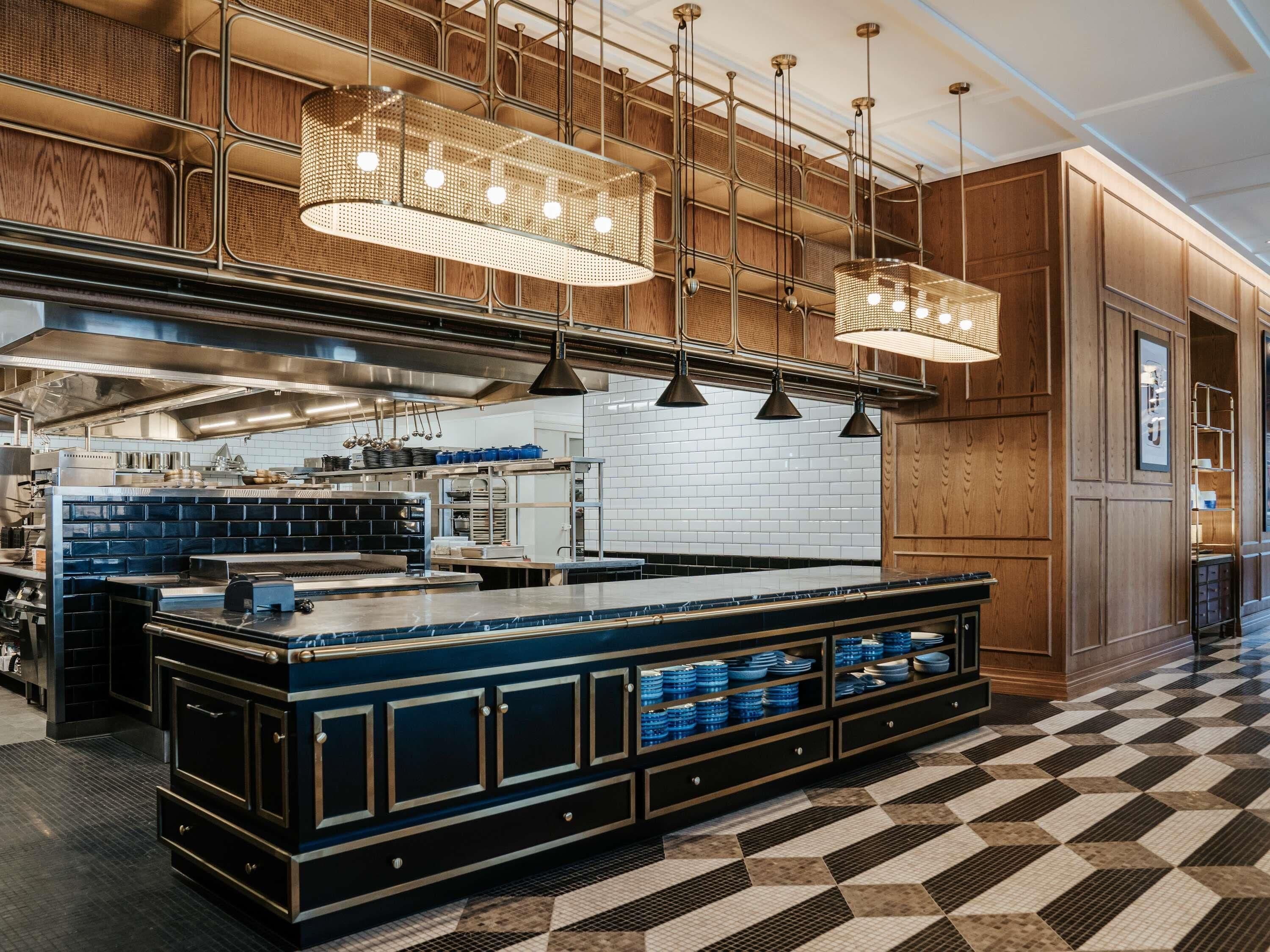 A modern kitchen with a central island, hanging pendant lights, and a checkered floor pattern.