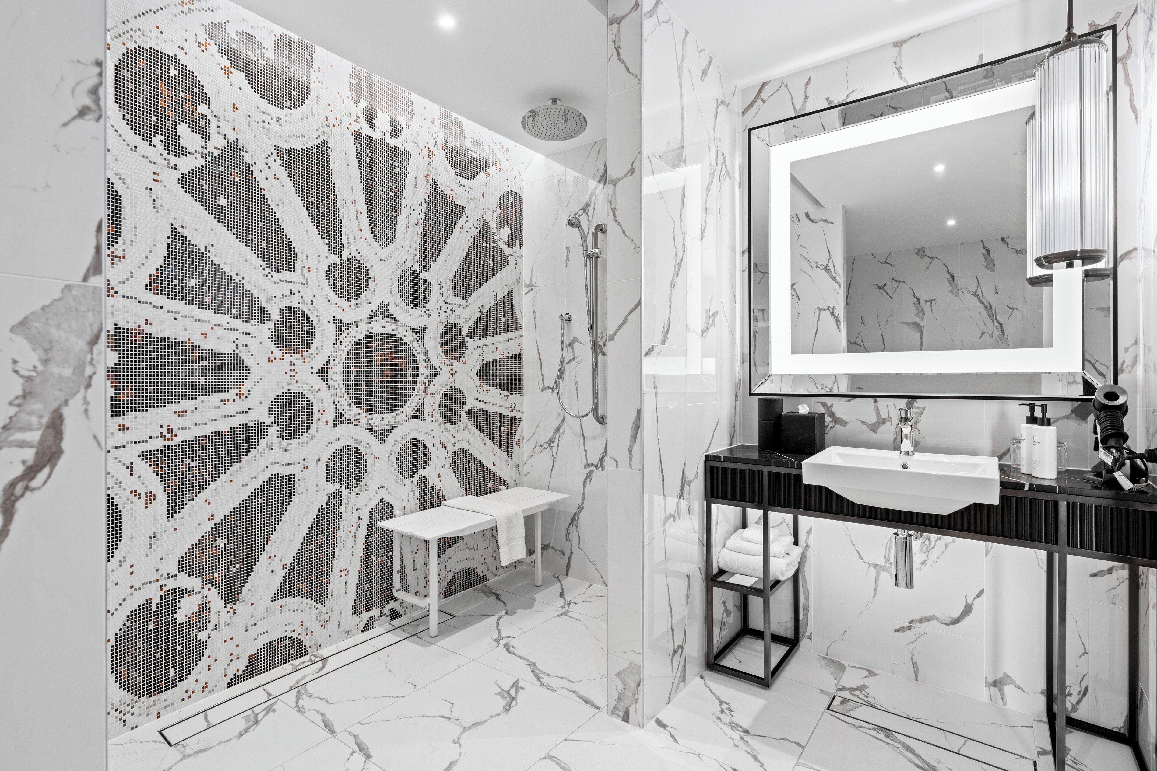 Une salle de bain moderne avec un sol en marbre, un grand miroir, un lavabo et un espace douche.