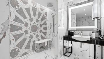 Un bagno moderno con pavimento in marmo, un grande specchio, un lavandino e uno spazio doccia.