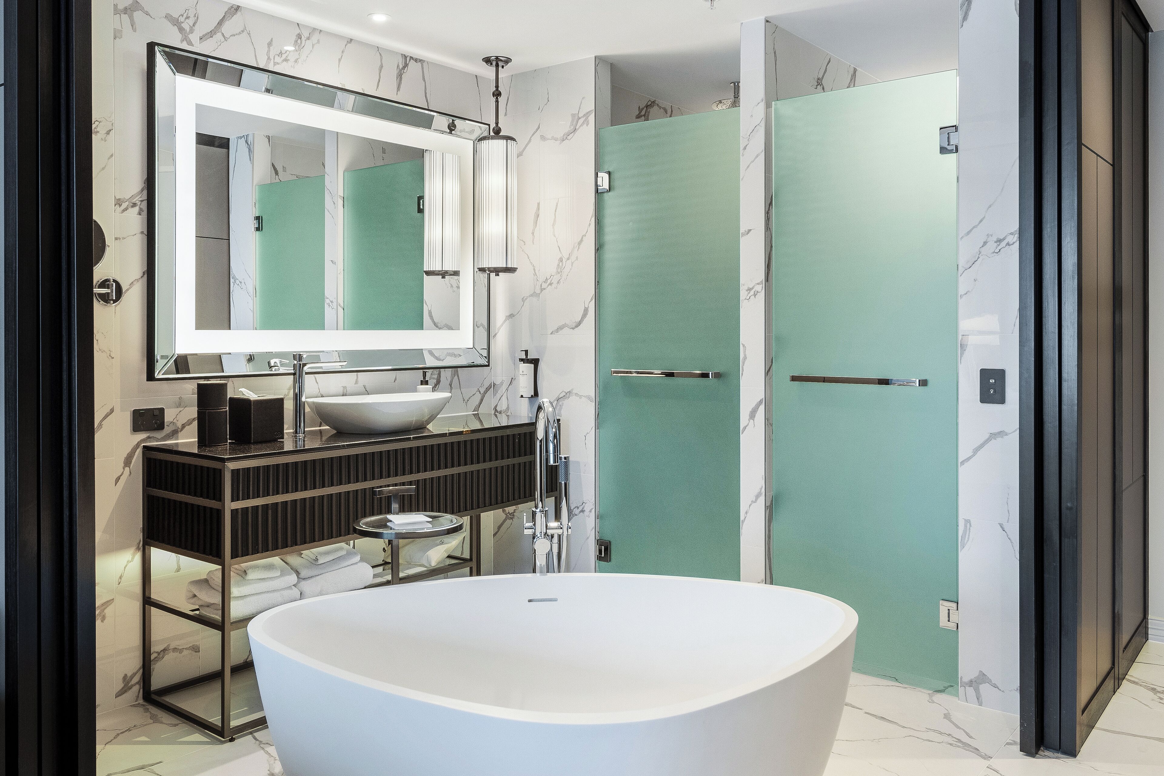 A modern bathroom with a freestanding bathtub, a large mirror, and a vanity with a sink and storage.