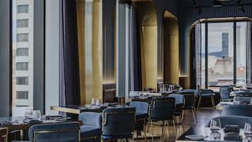 A modern restaurant interior with high ceilings, large windows, and a city view.