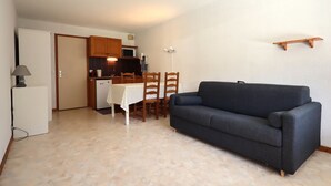 A compact living space with a kitchenette, a dining table, and a sofa.