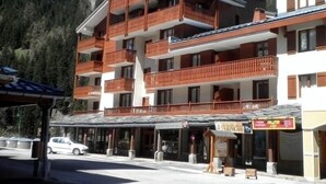 Ett hotell med flera våningar, balkonger, en överbyggd entré och en bergig bakgrund.