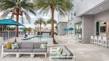 Una piscina al aire libre, sombrillas, sillones reclinables de piscina