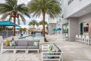 Una piscina al aire libre, sombrillas, sillones reclinables de piscina