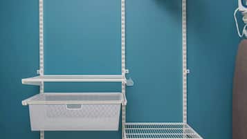 Una habitación con paredes verde azulado, un estante metálico blanco y un piso marrón.