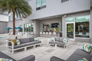 An outdoor patio area with grey sofas, white chairs, and a pool.