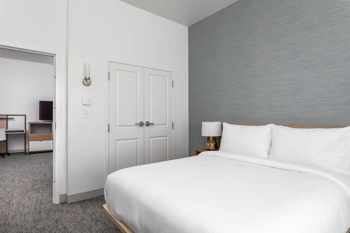 Una habitación de hotel con cama, escritorio y armario.