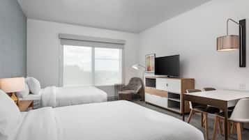 Een hotelkamer met twee bedden, een bureau, een stoel, een televisie en een raam.