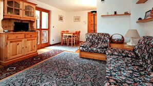 A cozy living room with wooden furniture, a patterned rug, and a television.