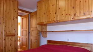 A room with wooden cabinets and a bed with a red bedspread.