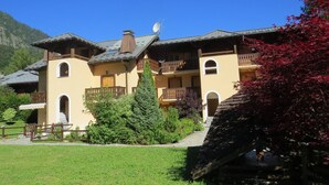 A two-story building with balconies, a satellite dish, and a mountain backdrop.