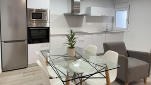 A modern kitchen with stainless steel appliances, a glass dining table, and white cabinetry.