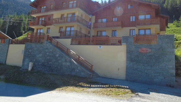 A multi-story hotel with balconies and a stone staircase leading to the entrance.