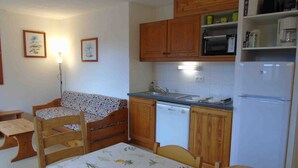 A compact kitchen with wooden cabinets, a dishwasher, and a refrigerator.