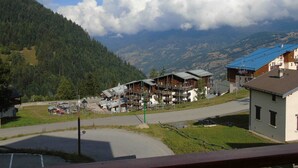 A mountain village with traditional wooden buildings, a ski lift, and a view of the surrounding hills.