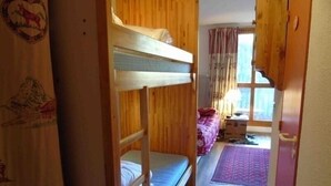 A room with bunk beds, a desk, a chair, and a window with curtains. - Charming studio for 4 near slopes with balcony, pets allowed (Valfréjus)