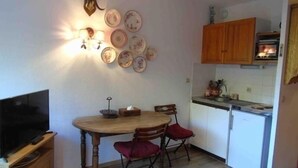 A compact kitchen with a dining table, chairs, and a TV. - Charming studio for 4 near slopes with balcony, pets allowed (Valfréjus)