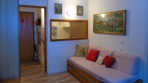 A living room with a sofa, a painting, and a mirror on the wall. - Cozy studio 4 ppl, near gondola & shops (Valfréjus)