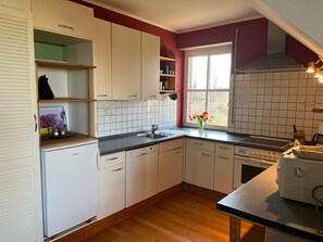 A kitchen with white cabinets, a black countertop, a window with a view, and a stove.