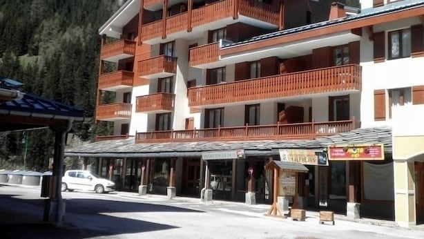 Un hôtel à plusieurs étages doté de balcons, d’une entrée couverte et surplombant un paysage montagneux.