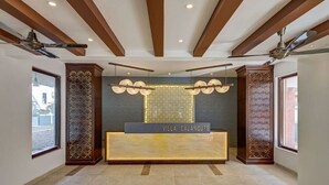 En receptionsdisk med texten ”VILLA CALANGUTE”, med en modern design, träpanel och en vägg med ett mönster bakom.