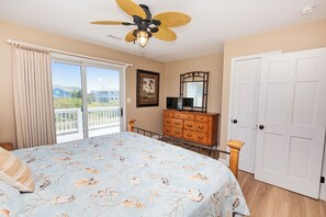 Un dormitorio con cama, cómoda, ventilador de techo, puerta y ventana con vistas.