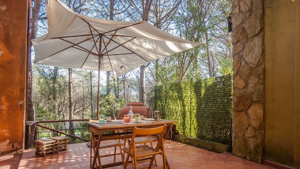 Patio esterno con tavolo, sedie e un ombrellone grande.