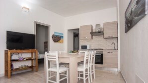 Una cucina moderna con forno a microonde, piano cottura e pensili in legno. È presente un'area pranzo con tavolo e sedie.