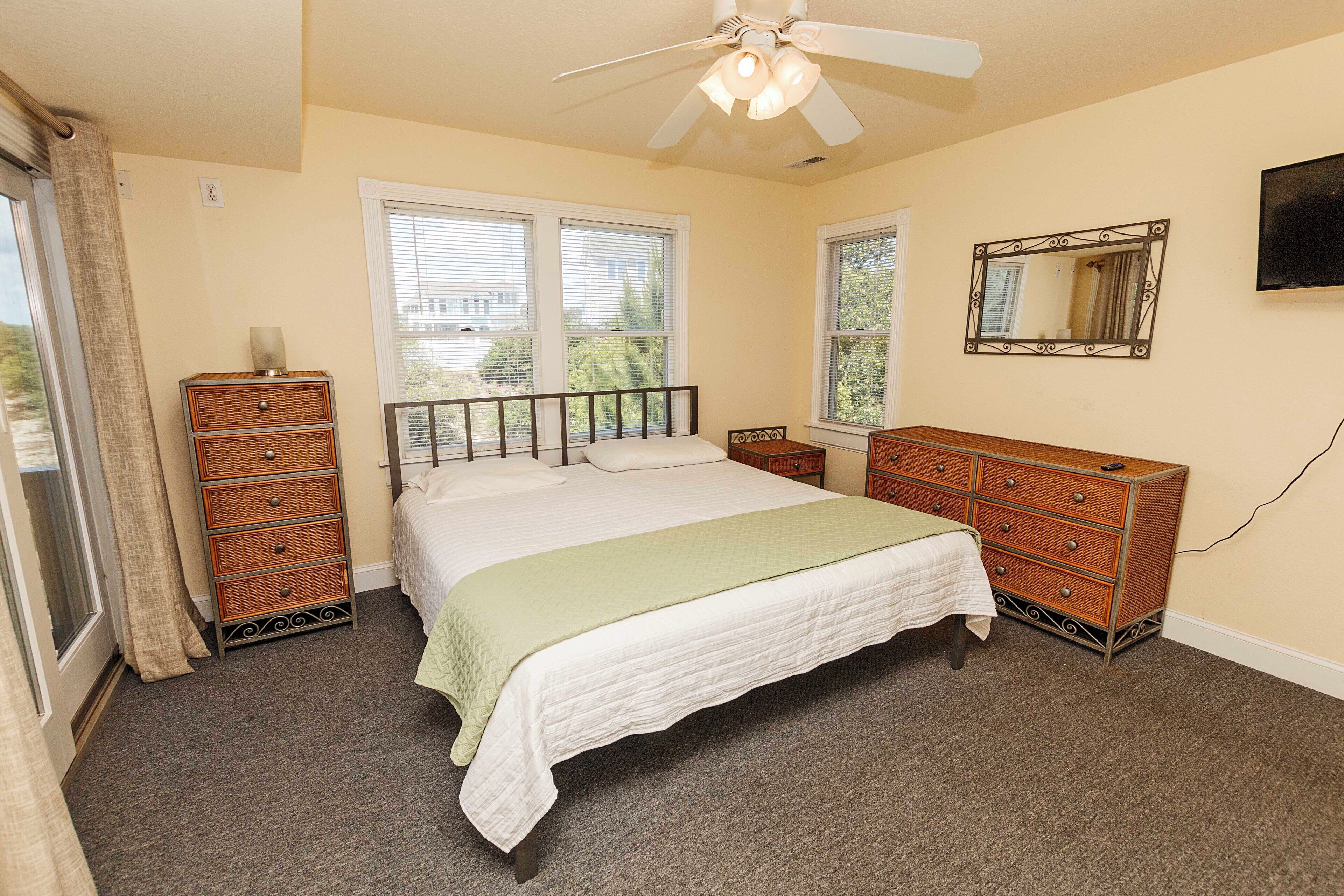 A bedroom with a bed, dresser, and a ceiling fan.