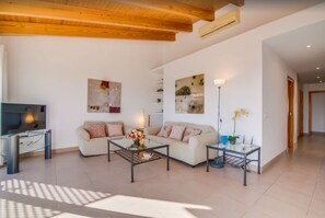 Ein geräumiges Wohnzimmer mit Fernseher, zwei Sofas, einem Couchtisch und Kunstwerken an den Wänden.