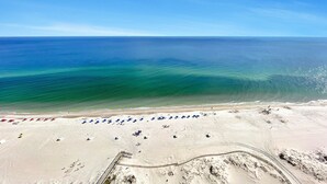 An aerial view of a beach with rows of sun loungers and a clear view of the ocean. - New Owner and New to the Rentals Market!  Lazy River/Slide! (Orange Beach)