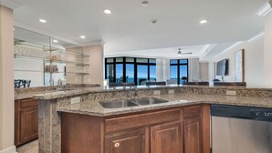 A modern kitchen with granite countertops, stainless steel appliances, and a large window offering a view of the ocean. - New Owner and New to the Rentals Market!  Lazy River/Slide! (Orange Beach)