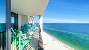 Enjoy the ocean view from this balcony with comfortable seating and a table.