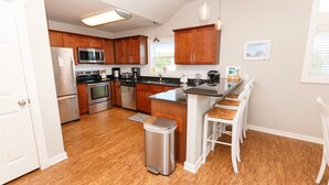 Una cocina moderna con armarios de madera, electrodomésticos de acero inoxidable y una barra con taburetes.