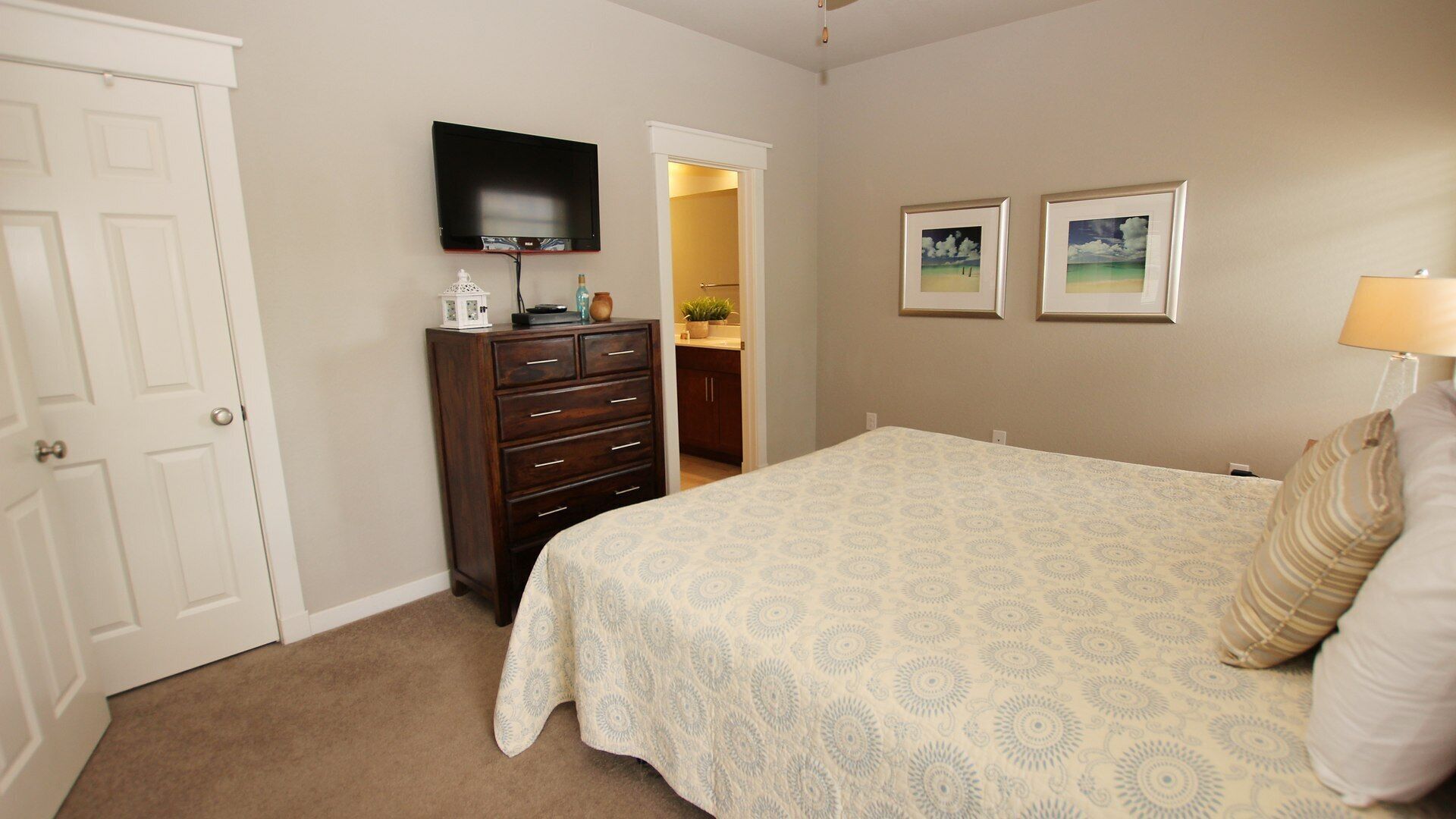 A bedroom with a bed, dresser, TV, and two framed pictures on the wall.
