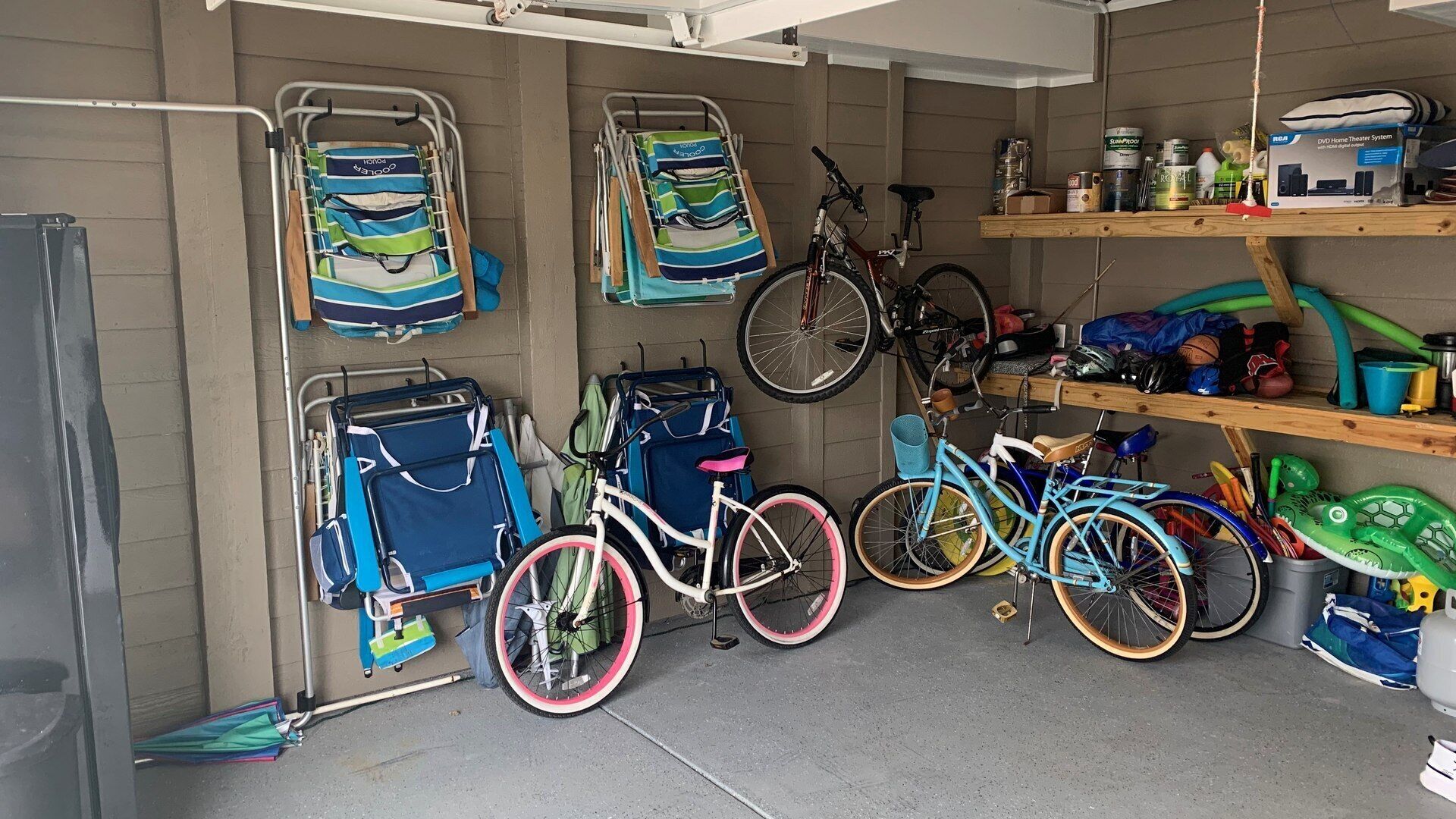 Un garage contenant des vélos, une poussette et une étagère remplie de divers objets.