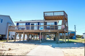 A two-story wooden structure with a balcony, a sign indicating a business, and a clear sky. - Semi-Oceanfront, 100 ft to beach access, Sun Decks, KH141, Blue Heaven (Kitty Hawk)